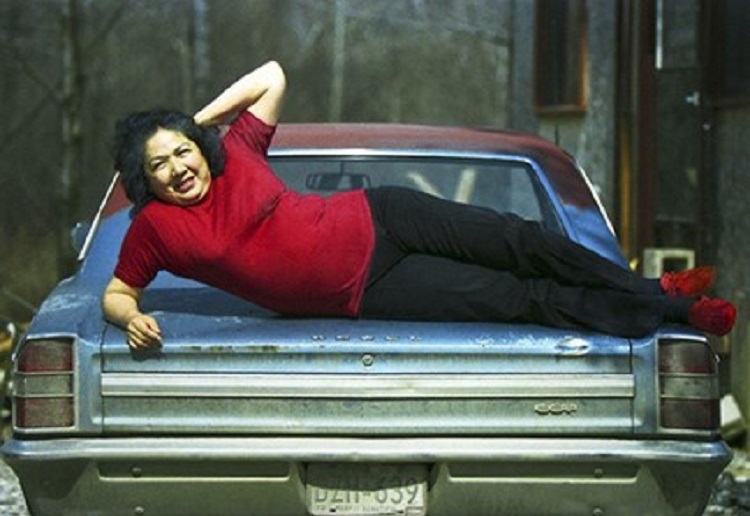 一个女人躺在一辆蓝色轿车的后备箱上